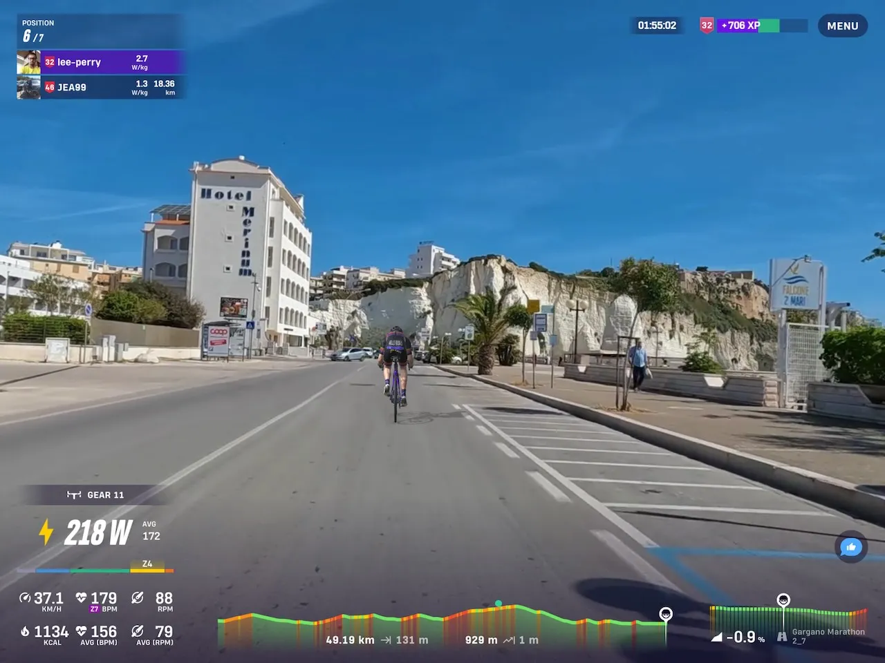 Screenshot from Rouvy showing a rider's avatar cycling towards white cliffs and blue skies
